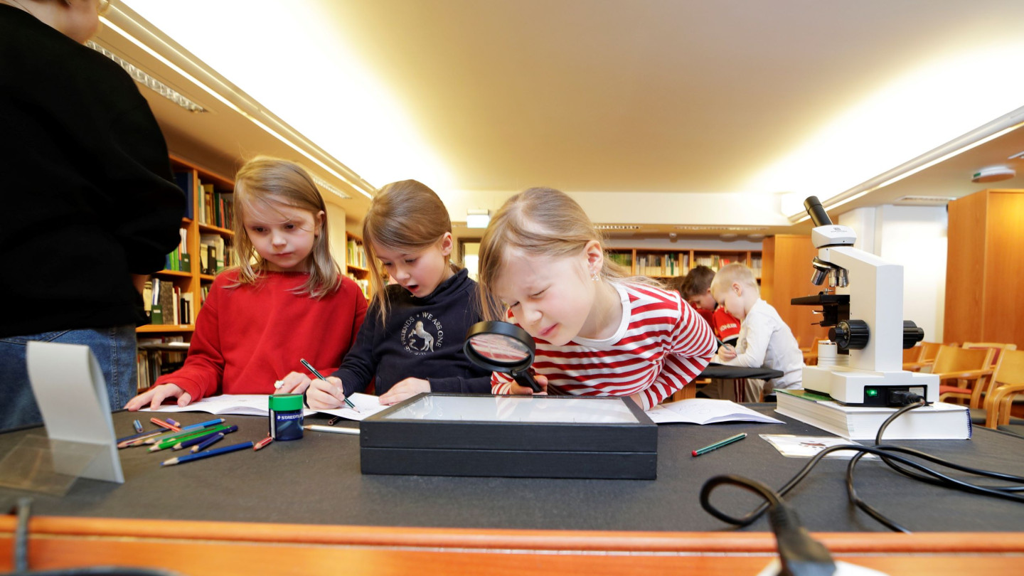 Koululaisia luontomuseossa pöydän ääressä.