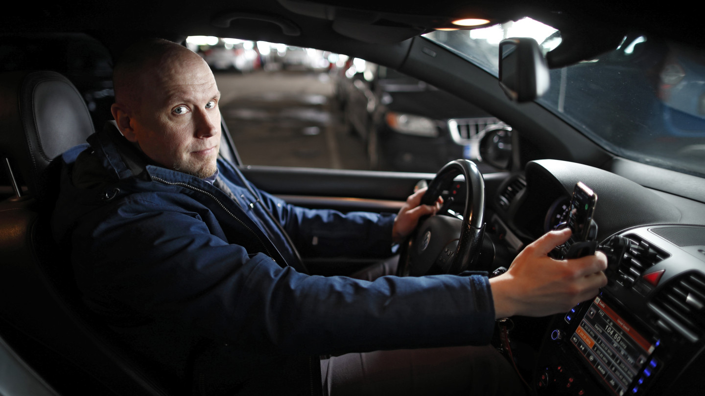 Apulaisprofessori Tuomo Kujala istuu autossa käyttäen samanaikaisesti kännykkää.