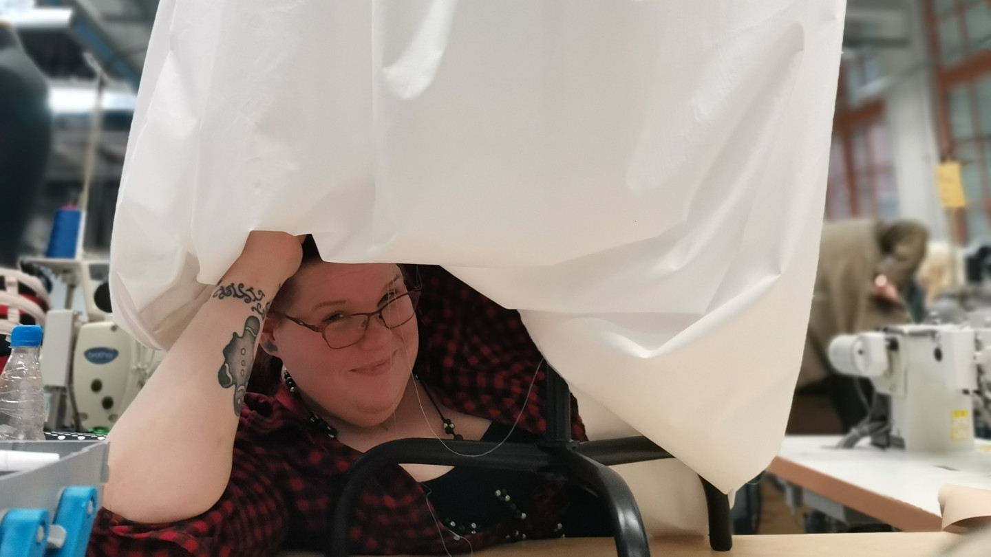 Aino kurkistaa kameraan ompelemansa valkoisen rokokoomekon alta.