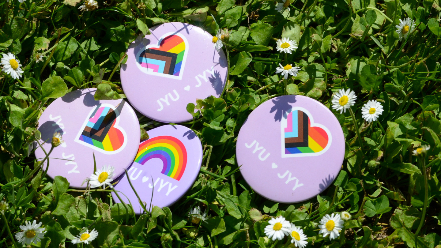 Pride-teemaisia pinssejä nurmikolla.