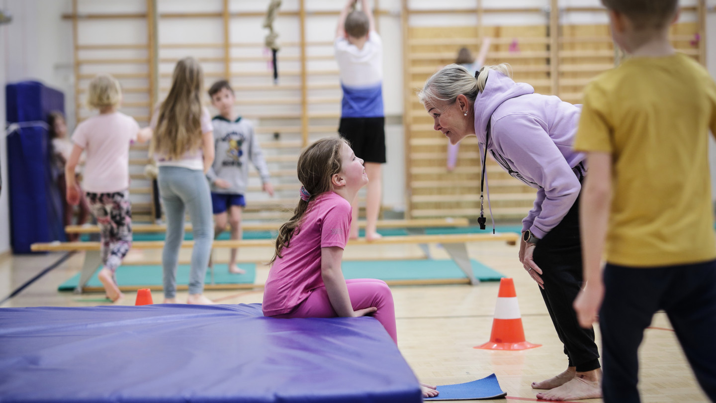 Lapsia ja opettaja liikuntasalissa