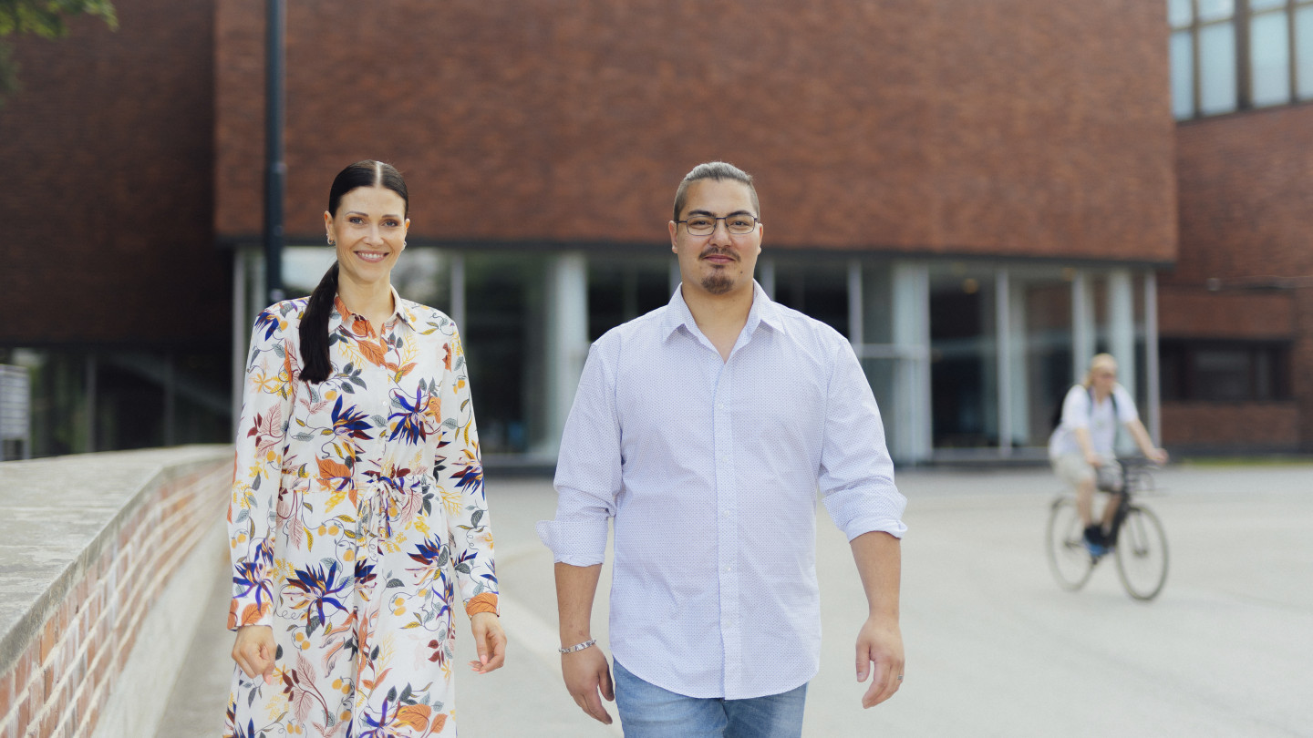 Two persons walking in front of the JYU main building.