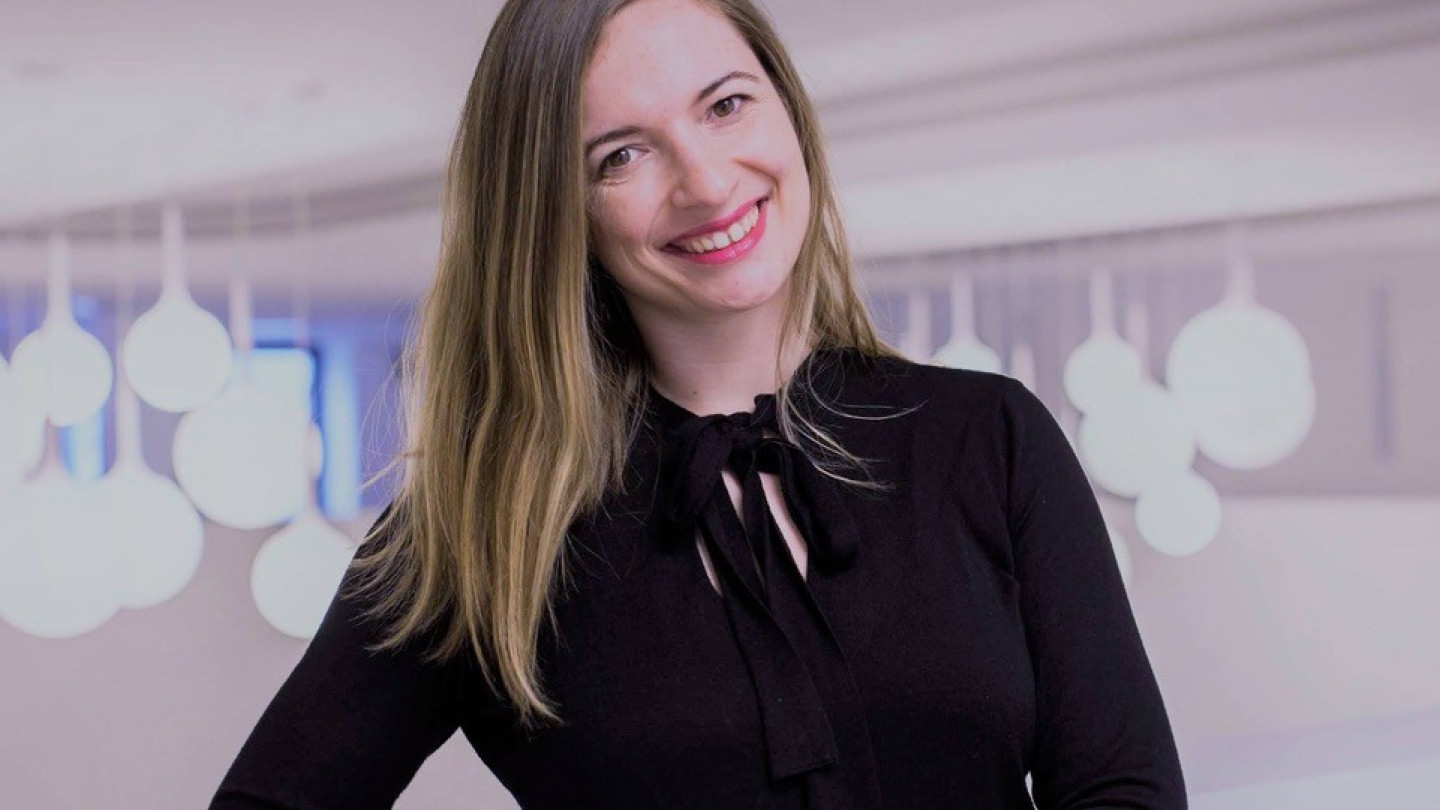 Tutkija Eva Klusová hymyilee ja nojaa kaidetta vasten.