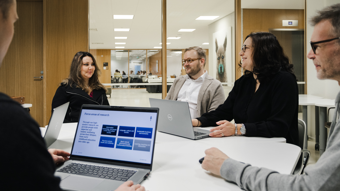 Kuvituskuva, ihmisiä keskustelemassa pöydän ympärillä.