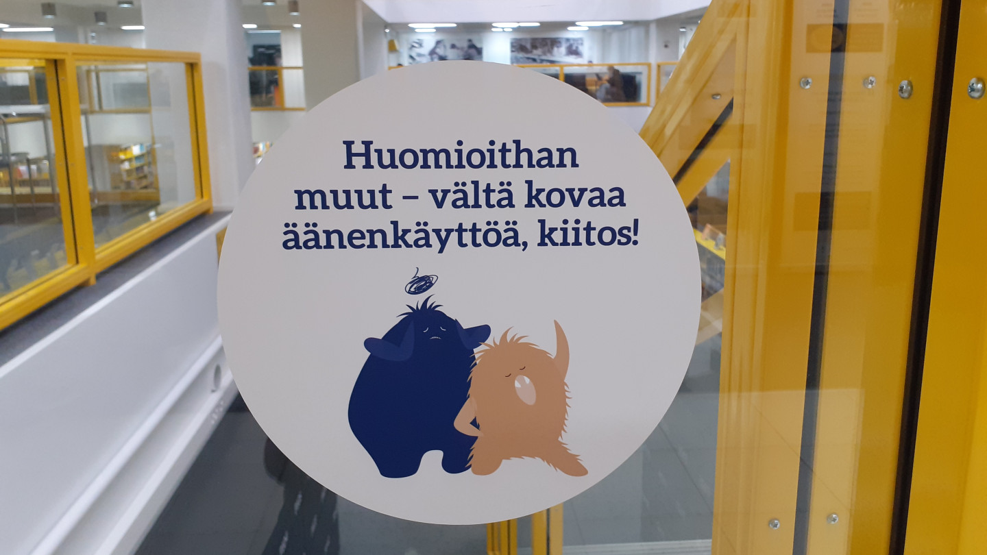 Lähde-kirjaston opaste, jossa kehotetaan välttämään kovaa äänenkäyttöä.