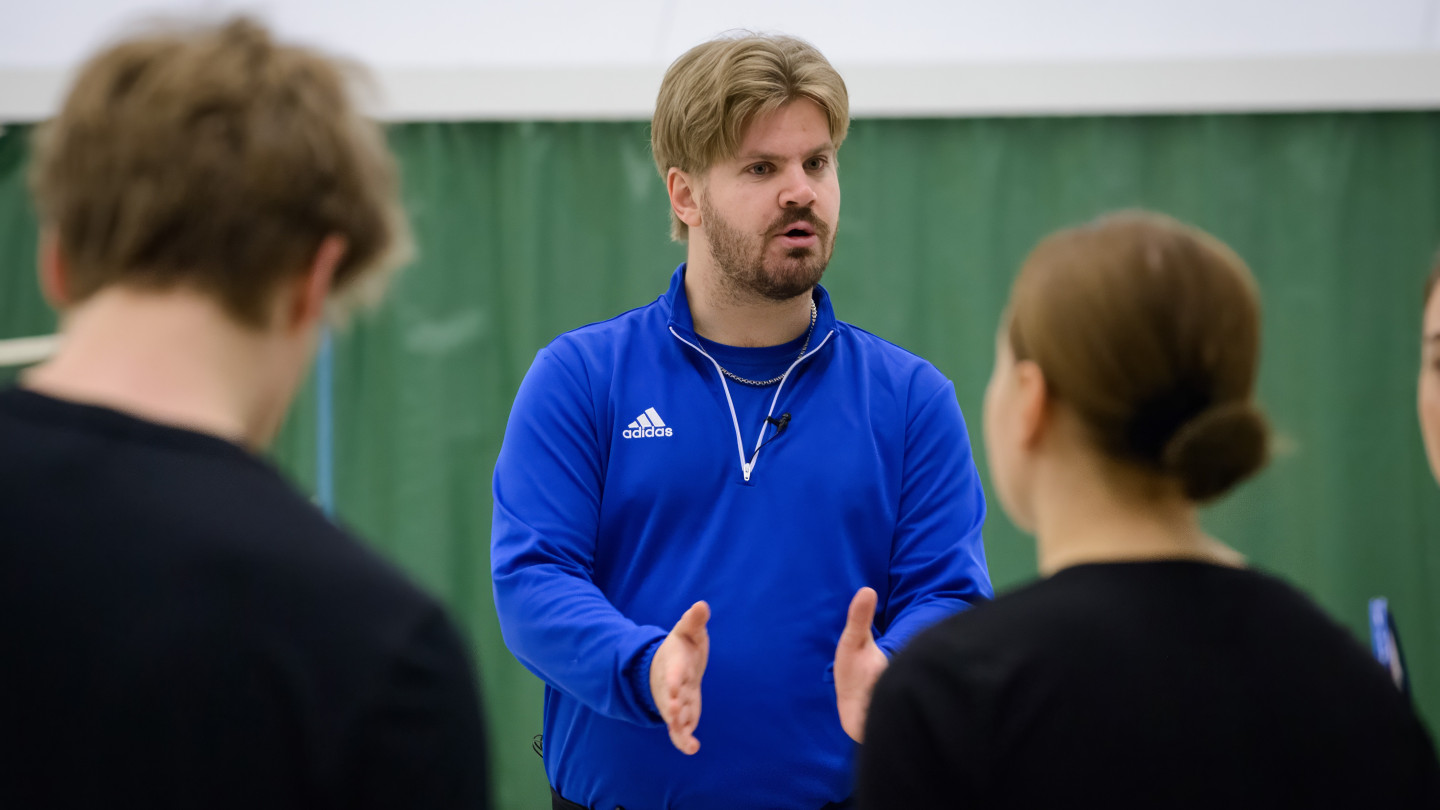 Ihminen ohjaamassa liikuntaa salissa