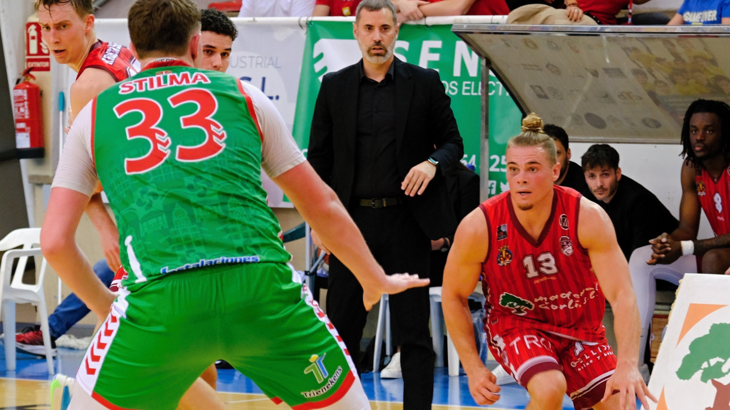 Koripallonpelaajat pelitilanteessa kentällä, valmentaja seutaa sivusta