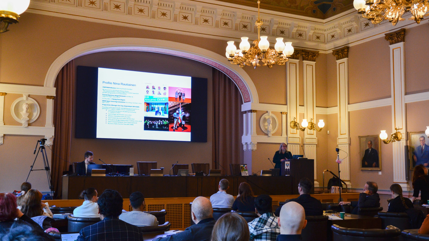 Kaupungintalon juhlasali täynnä ihmisiä ja esitys käynnissä