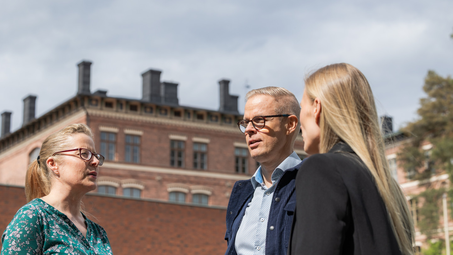 Kaksi naista ja mies juttelevat ulkona.