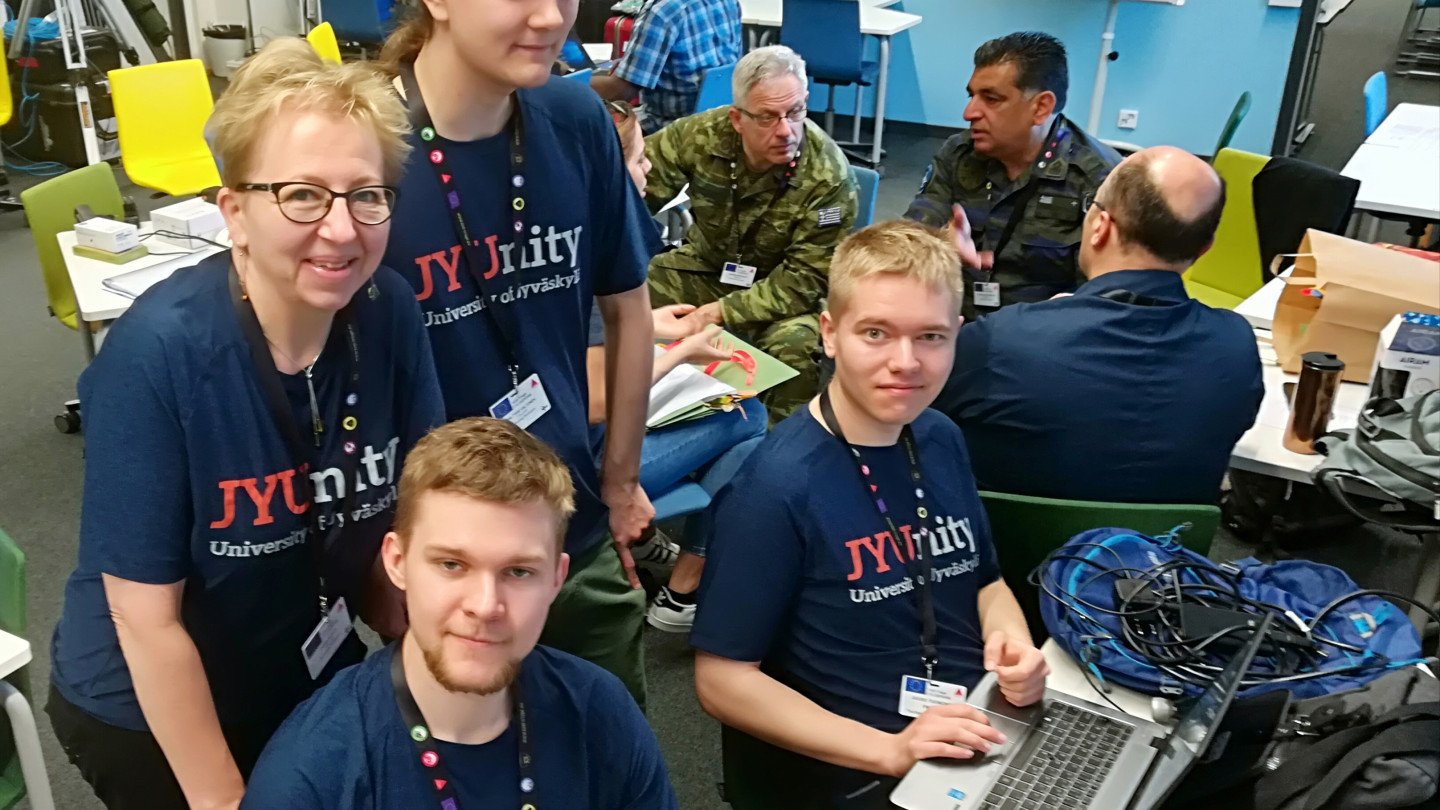 Jyväskylän yliopiston paikka Mikkelin FTX Disperse -harjoituksen operointikeskuksessa Kreikan puolustusvoimien vieressä. Takana Jaana Kuula ja Waltteri Valtonen, edessä Esko Hanell ja Juuso Tuononen.