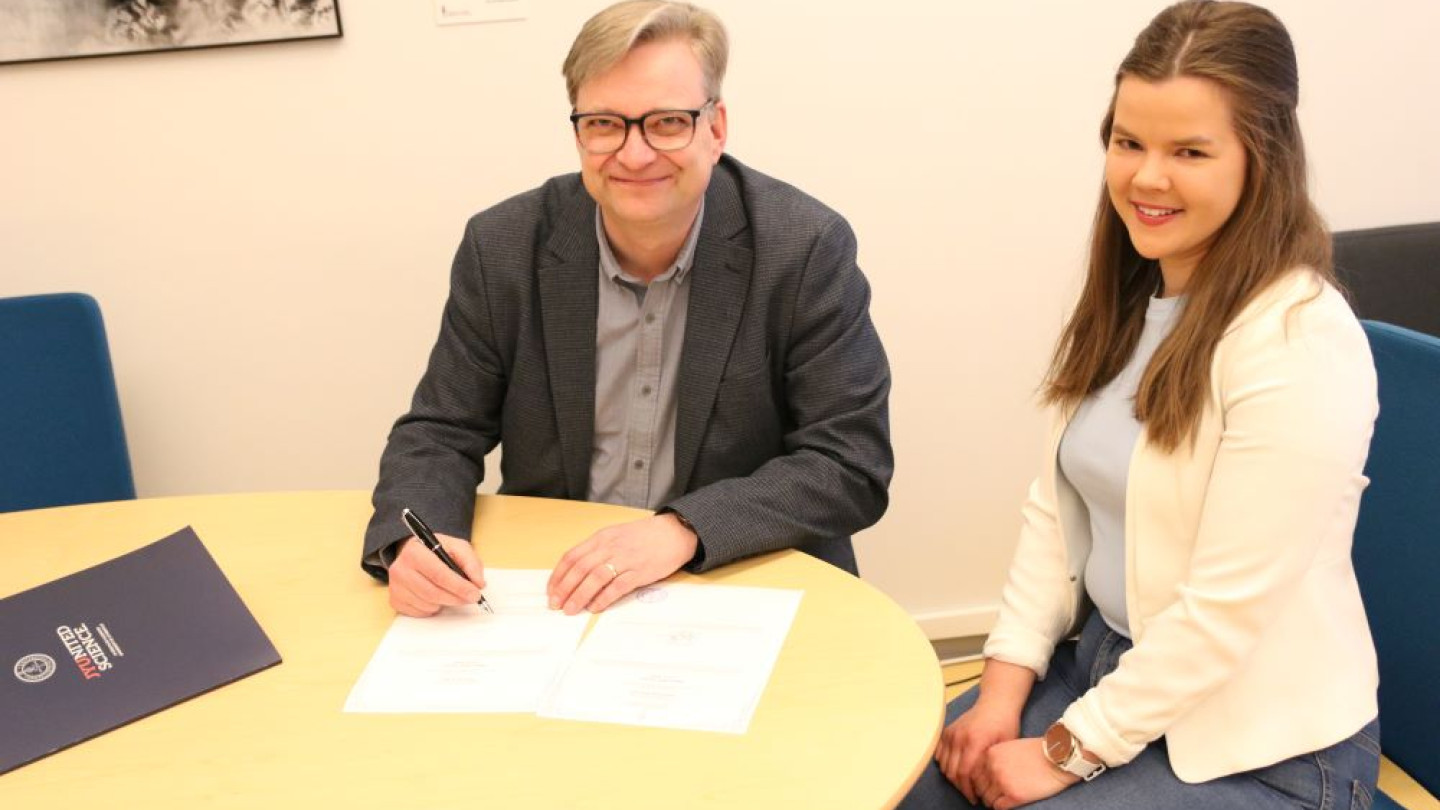 Dekaani Jari Ojala allekirjoittamassa viimeistä paperista tutkintotodistusta, jonka saaja oli filosofian maisteriksi valmistuva Mona Sainio. Kuvaaja: Joonas Niemi