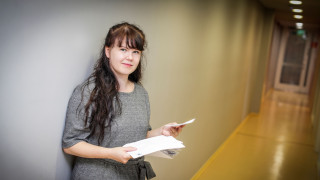 Tutkijatohtori Emilia Leinonen seisoo kirjeitä kädessään käytävällä yhteiskuntatieteiden ja filosofian laitoksella.