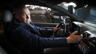 Apulaisprofessori Tuomo Kujala istuu autossa käyttäen samanaikaisesti kännykkää.