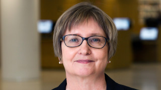 Sirpa Tenhunen, hänellä on lyhyet tummanruskeat hiukset ja silmälasit. Yllään hänellä on musta pikkutakki.