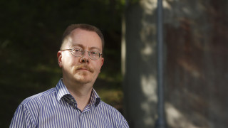 Pasi Ihalainen, jolla on ruskeat lyhyet hiukset ja silmälasit. Yllään hänelllä on vaaleansininen lyhythihainen kauluspaita.