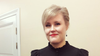 Riina Turunen väitöstilaisuudessaan mustassa mekossa.