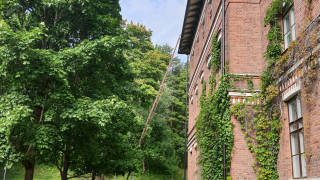 Green grass and trees next to Historica buildings terracotta wall.