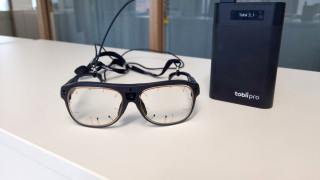 Kuvassa valkoisella tasolla silmälasit, jotka mittaavat silmänliikkeitä.