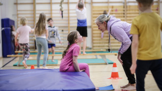 Lapsia ja opettaja liikuntasalissa