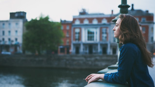 Woman smoking cigarette on a bridge in a city.