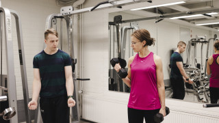 Kaksi henkilöä salilla tekemässä voimaharjoittelua