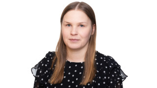 Elsa katsoo kameraan, hänellä on musta pilkukas paita. Elsa is looking at the camera, she is wearing a black shirt with dots.