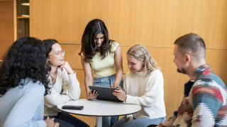 Five students sitting together on a university campus