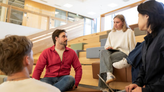 Four students sit together and study on a university campus.