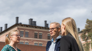 Kaksi naista ja mies juttelevat ulkona.