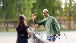 A woman and a man playing tennis and giving a high five to each other.