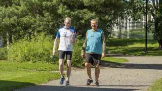 Kaksi henkilöä kävelee puistotietä