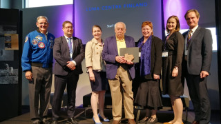 LUMAkeskus Suomen edustajat vastaanottamassa palkintoa Houstonin avaruuskeskuksessa. Kuvassa vasemmalta oikealle: astronautti Bill McArthur, Jan Lundell, Outi Haatainen, Johnson Space Centerin exjohtaja George Abbey, Maija Aksela, Anette Markula ja IPN2018 konferenssin puheenjohtaja Bruce Van Dyk.
