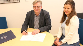 Dekaani Jari Ojala allekirjoittamassa viimeistä paperista tutkintotodistusta, jonka saaja oli filosofian maisteriksi valmistuva Mona Sainio. Kuvaaja: Joonas Niemi