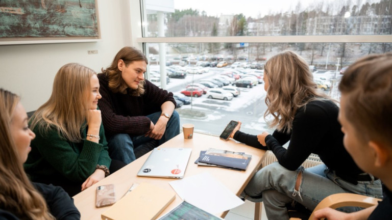 Opiskelijoita istumassa Agorassa pöydän ääressä töitä tekemässä.