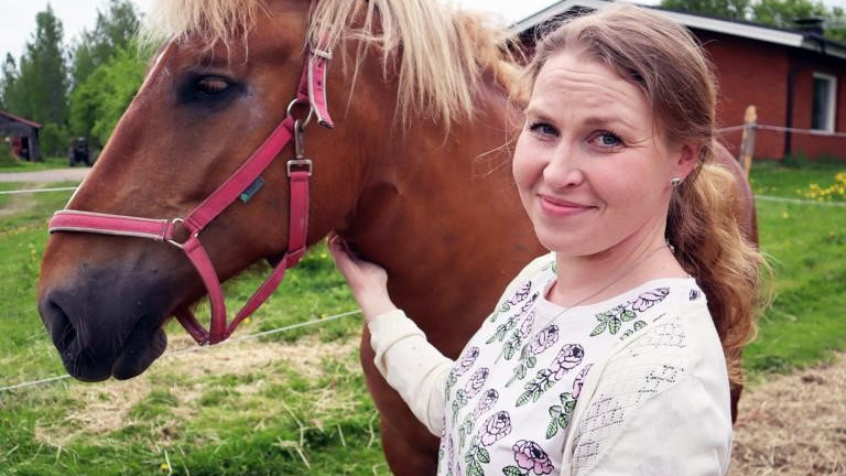 Irene Kuhmonen pitelee kiinni hevosensa päitsistä kotipihallaan.