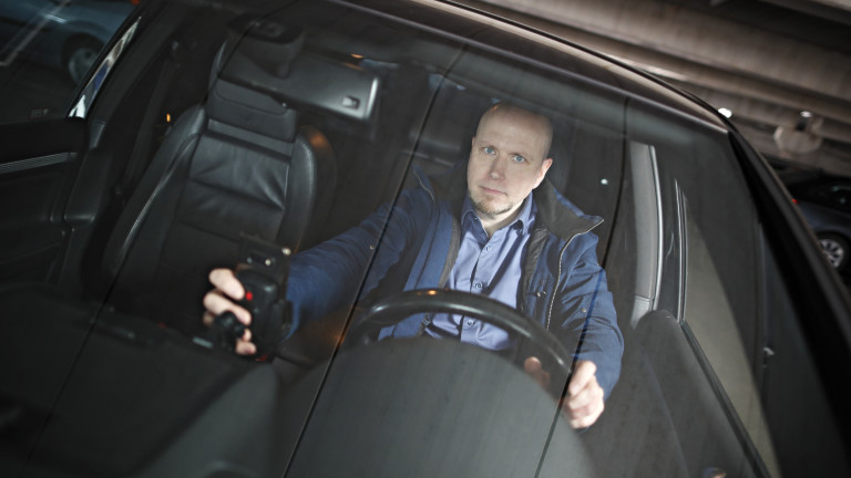 Apulaisprofessori Tuomo Kujala istuu autossa ja käyttää kännykkää.