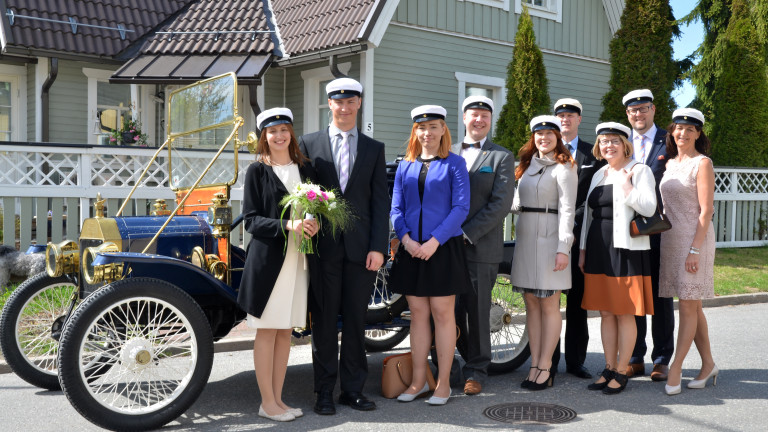 Iloisia ihmisiä vanhan hienon auton edessä