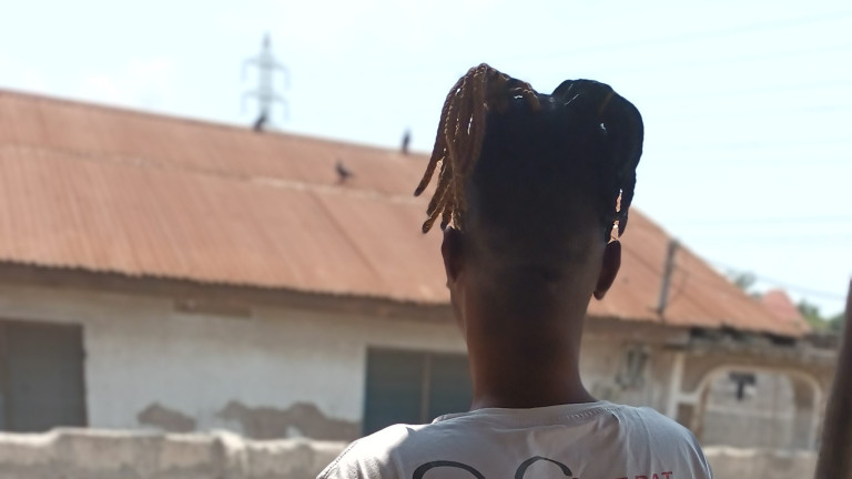 Laura's informant from behind. She has dark skin and dreadlocks.