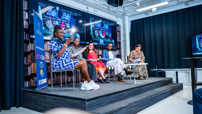 Dr. Elizabeth Eta explains a point during the panel discussion as copanelists (LR) Judith, Irmeli, Karembe and Sirpa look on.