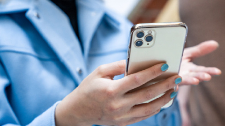 Ihminen pitää puhelinta kädessään