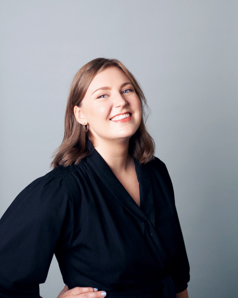 Sonja hymyilee kameralle. Oikea käsi on lanteella.
