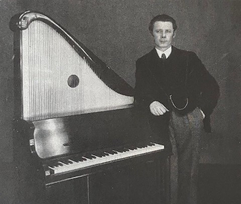 Juhani Pohjanmies nojaa pianokanteleeseen. Kuva on mustavalkoinen. Pohjanmiehellä on vasen käsi taskussa.