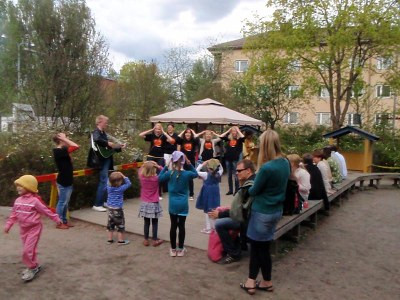 kielikampuksen jäsenet kielisuihkuttamassa lapsia keväisellä pihalla